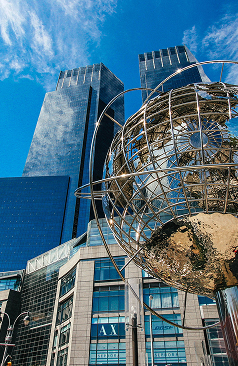 Globe sculpture in front of glass skyscrapers