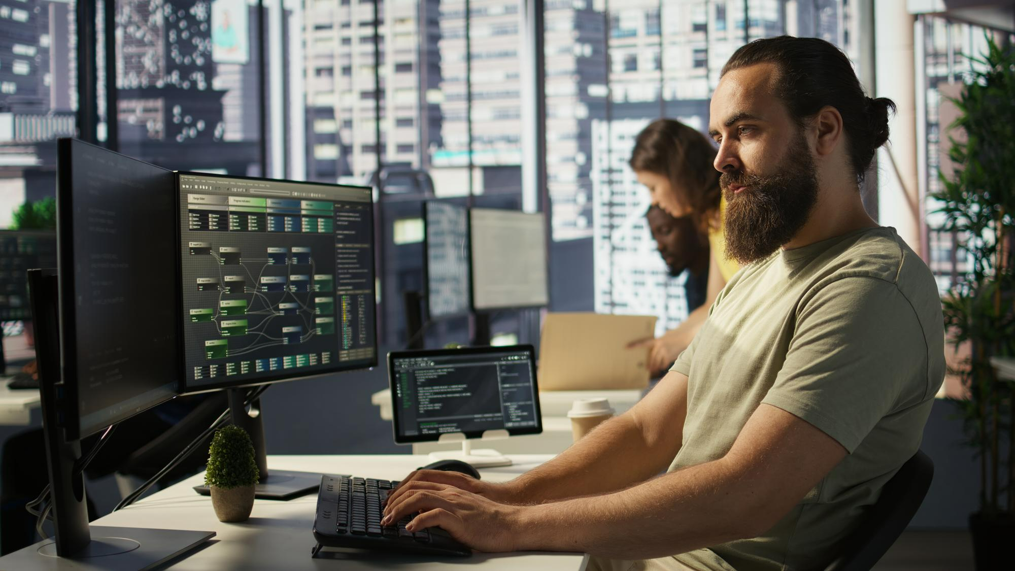 Engineer reviewing a workflow on dual monitors in an office